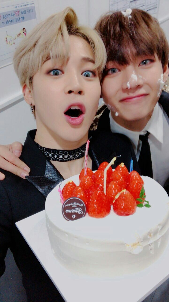 two people posing for a photo with a cake and candles in front of their faces