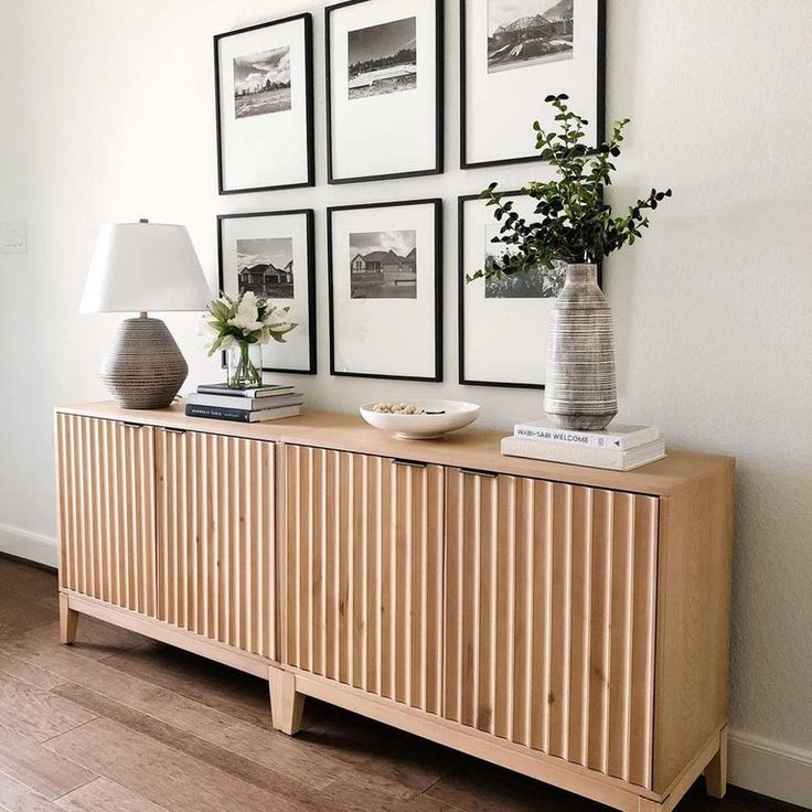 a wooden sideboard with pictures on the wall above it