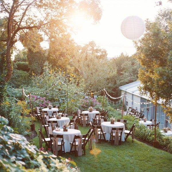 an outdoor dining area with tables and chairs in the middle of it, surrounded by greenery