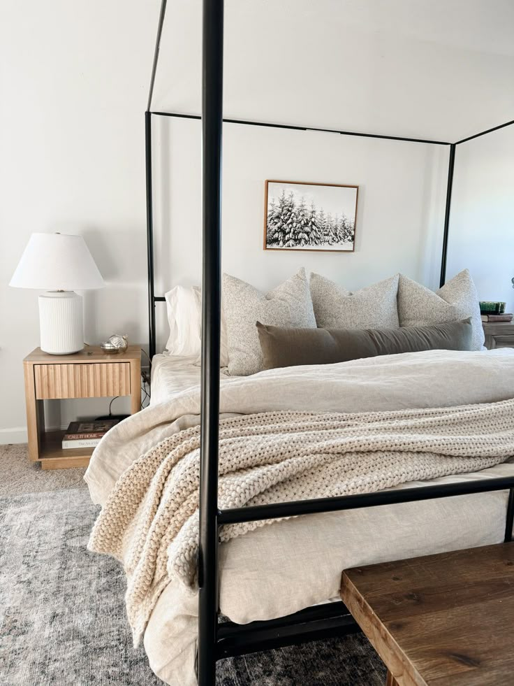 a canopy bed with white sheets and pillows