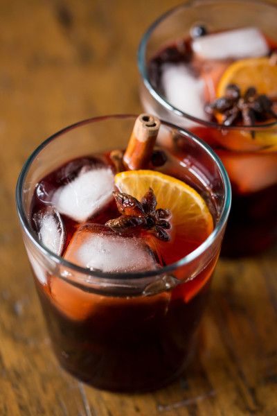 two glasses filled with drinks sitting on top of a wooden table