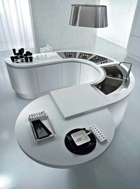 a modern kitchen with white counter tops and appliances on the counters, along with a circular dining table