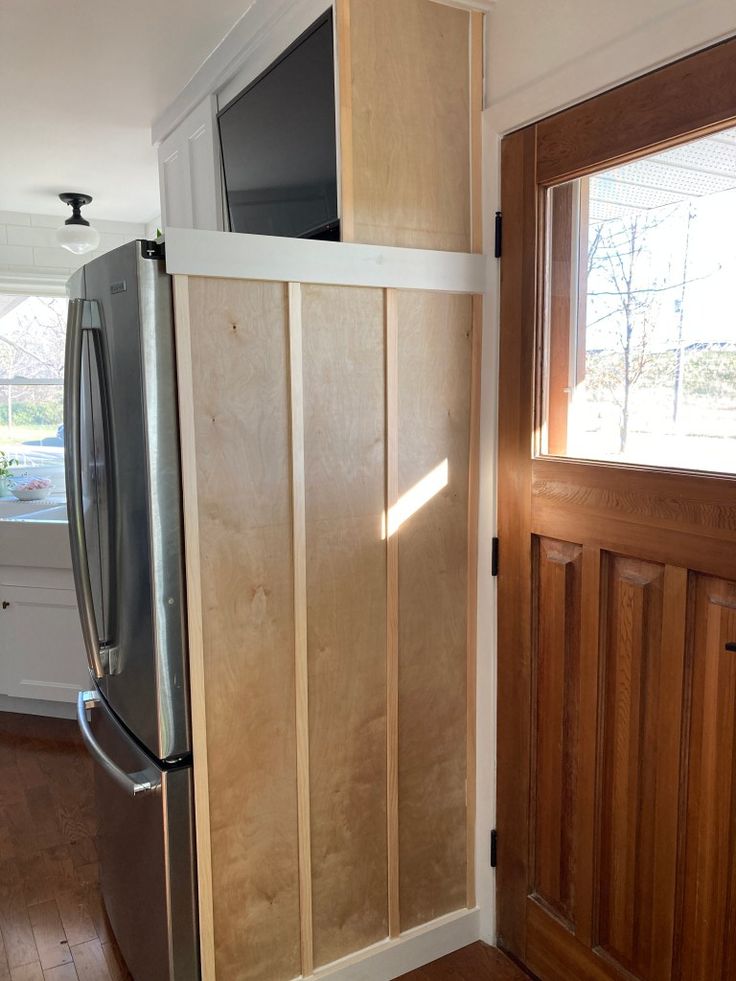 a refrigerator freezer sitting inside of a kitchen next to a wooden paneled wall