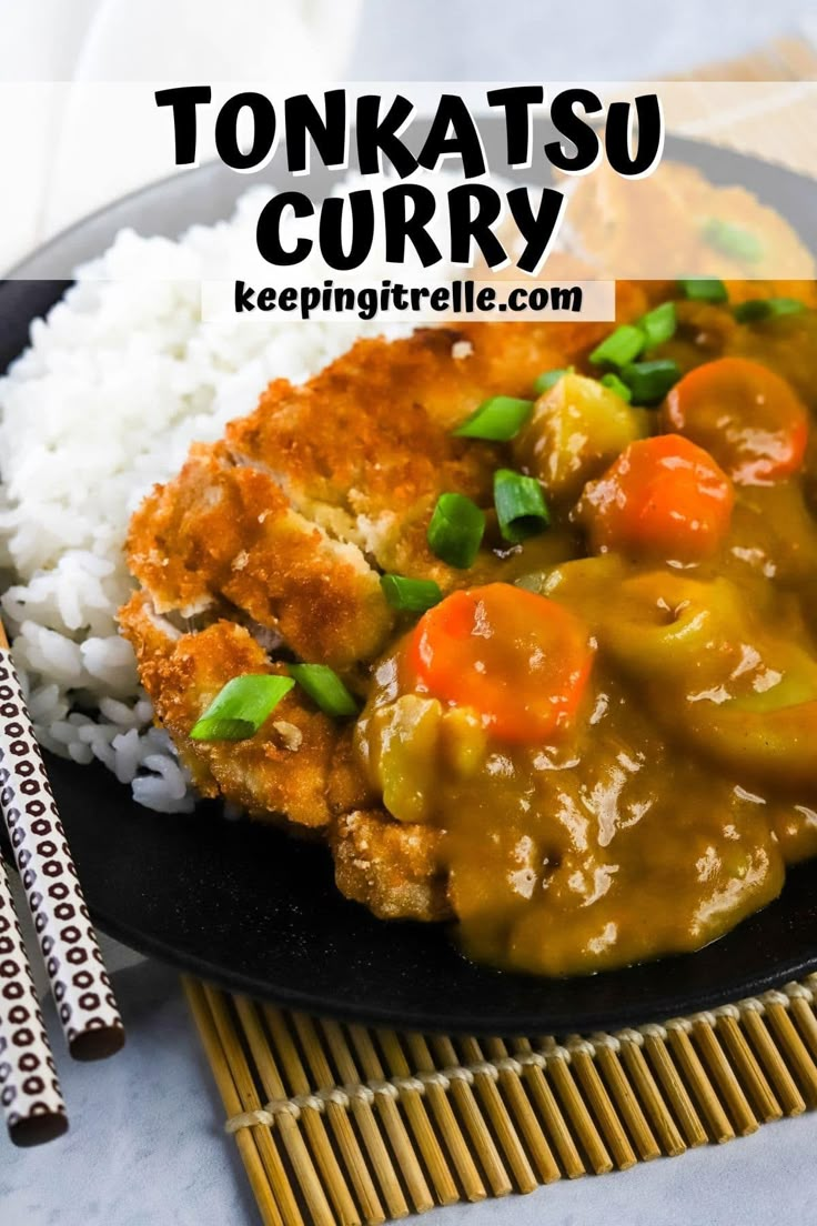 a black plate topped with rice and meat covered in gravy next to chopsticks