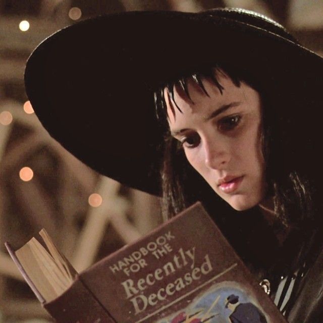 a woman wearing a black hat and holding a book