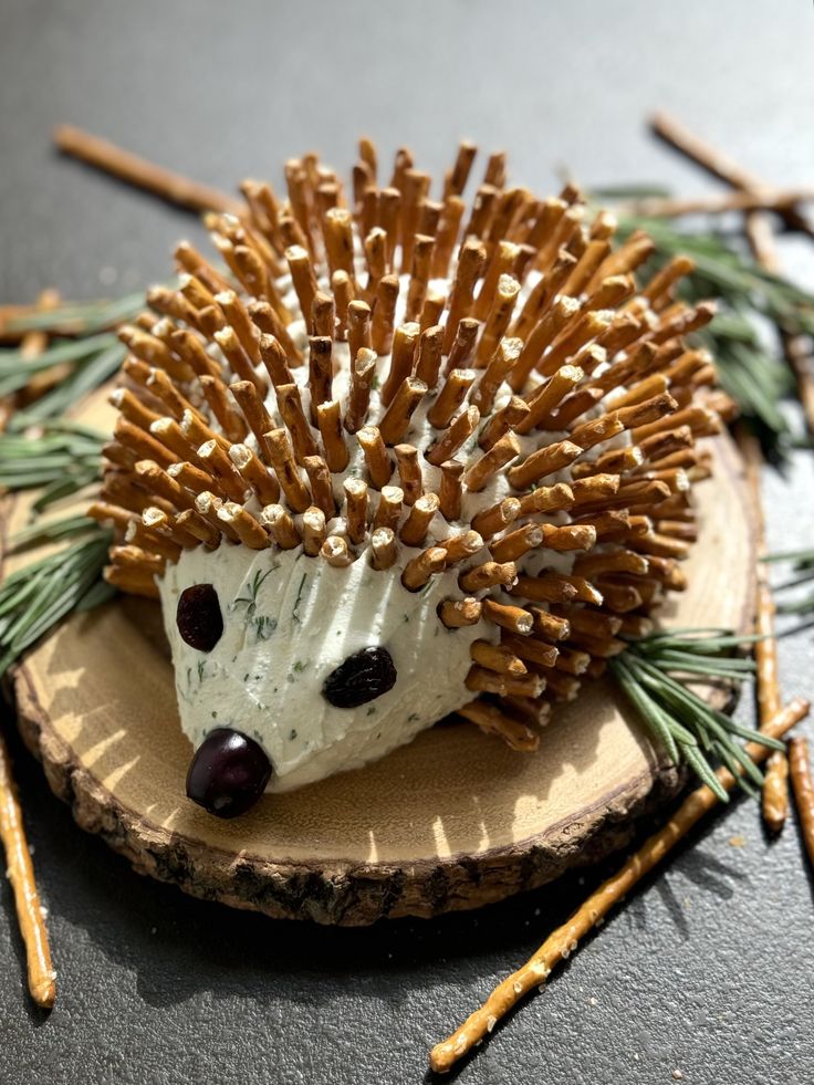 a hedgehog figurine sitting on top of a piece of wood with sticks sticking out of it