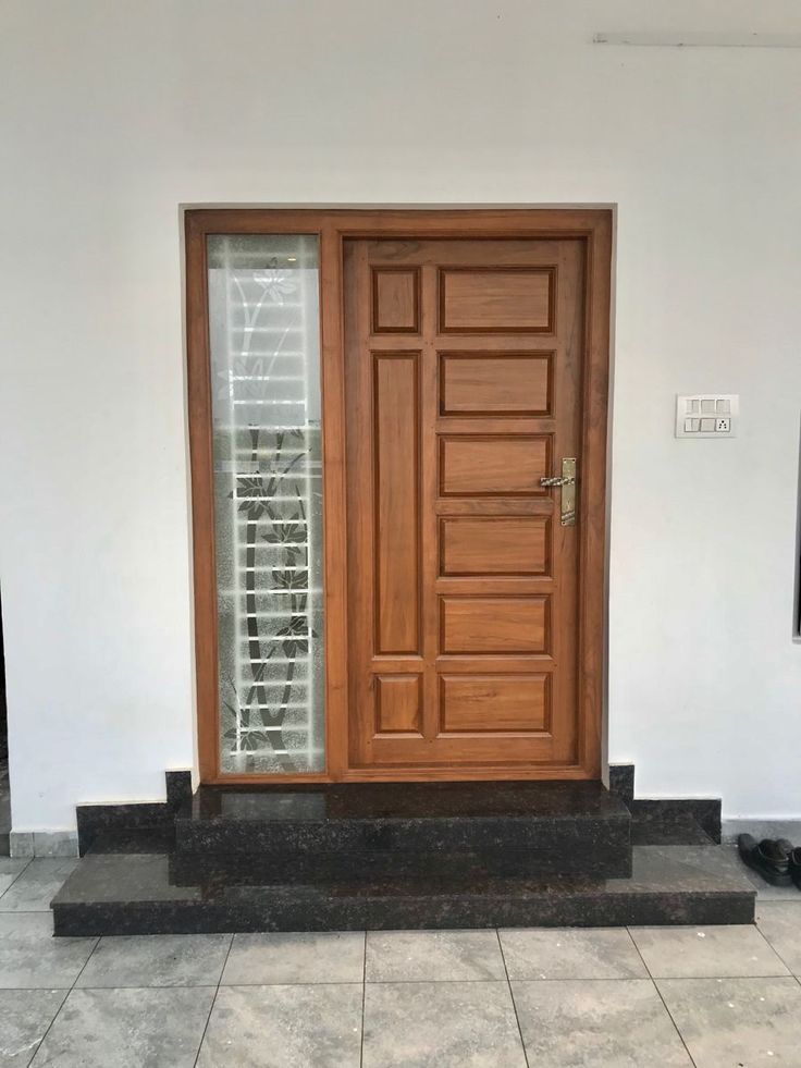 a wooden door sitting on the side of a white wall next to a pair of black shoes