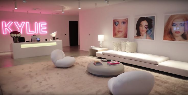 a living room filled with white furniture and pictures on the wall