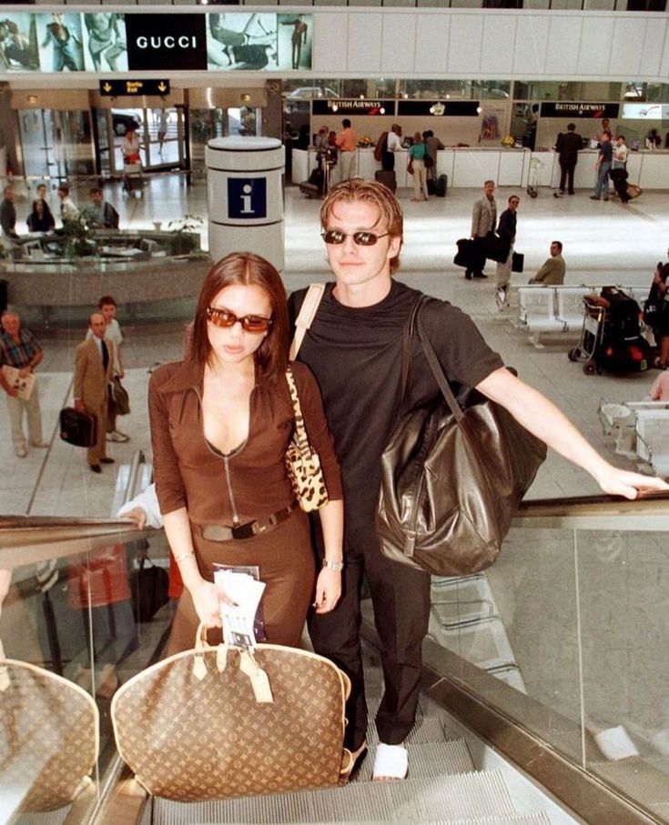 a man and woman are standing on an escalator with their luggage in hand