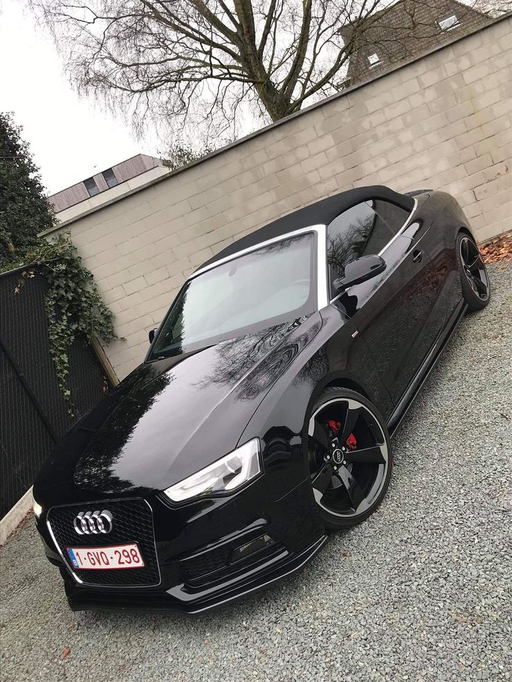 a black car parked in front of a brick wall