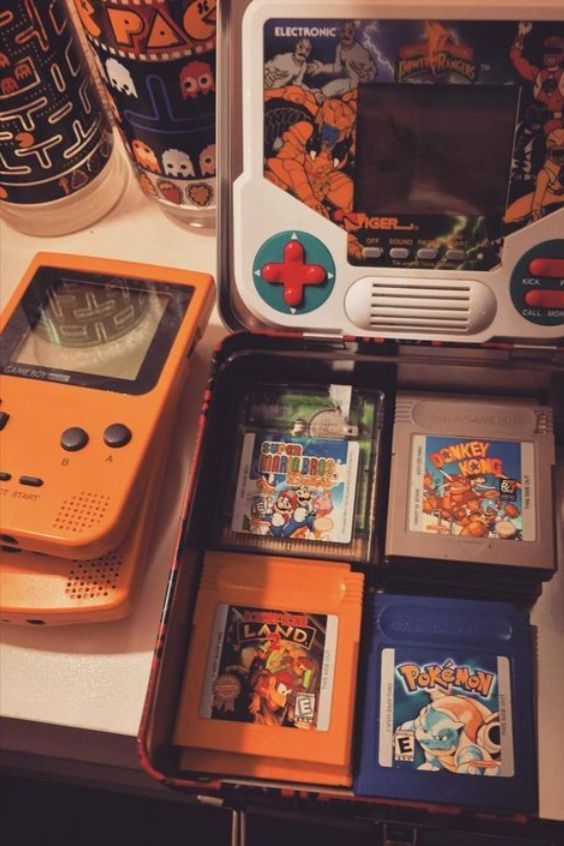 an orange gameboy sitting on top of a table next to other games and accessories