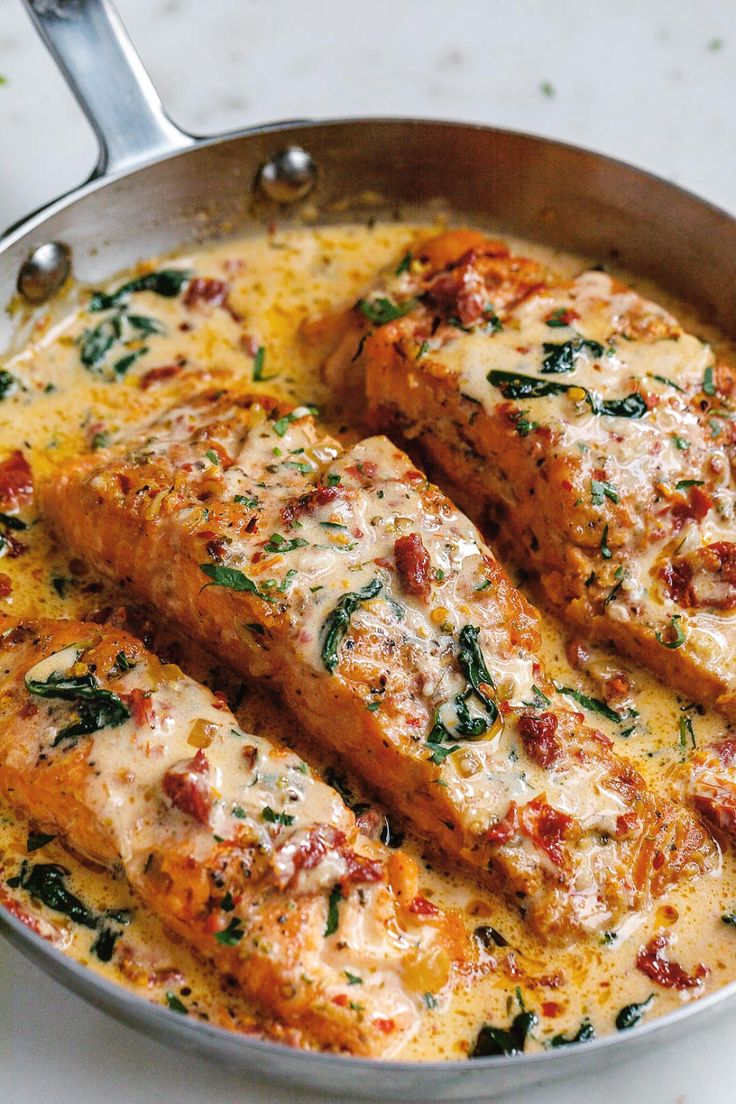 two pieces of meat in a pan with cheese and spinach on the side, ready to be eaten