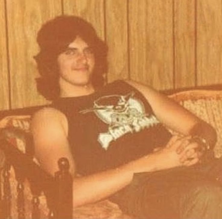 a young man sitting on top of a couch next to a wooden paneled wall