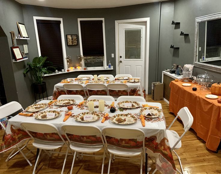 a dining room set up for a party with orange tablecloths and white chairs