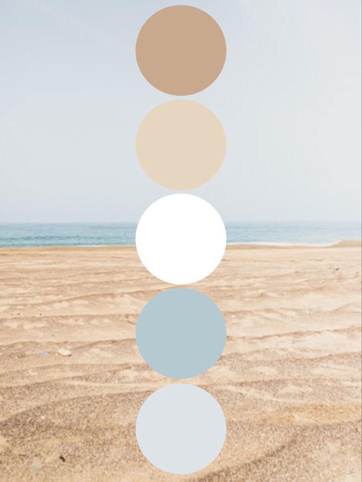 four circles are arranged in the shape of five different colors on a sandy beach near the ocean