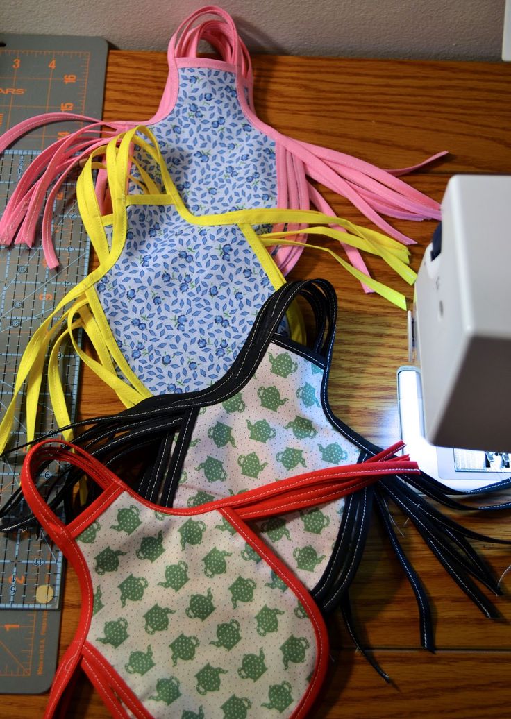 three bibs are laid out on a table next to a sewing machine and ruler