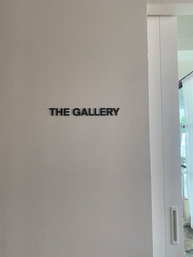 the gallery sign is mounted on the wall in front of a door that leads to another room