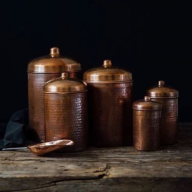 copper canisters are sitting on a wooden table