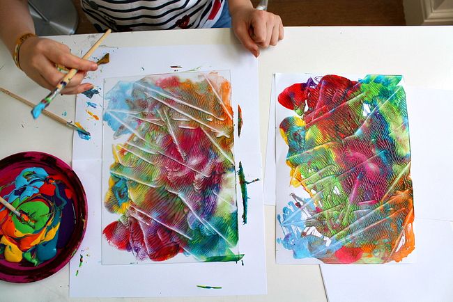 two children's hands painting on paper with watercolors