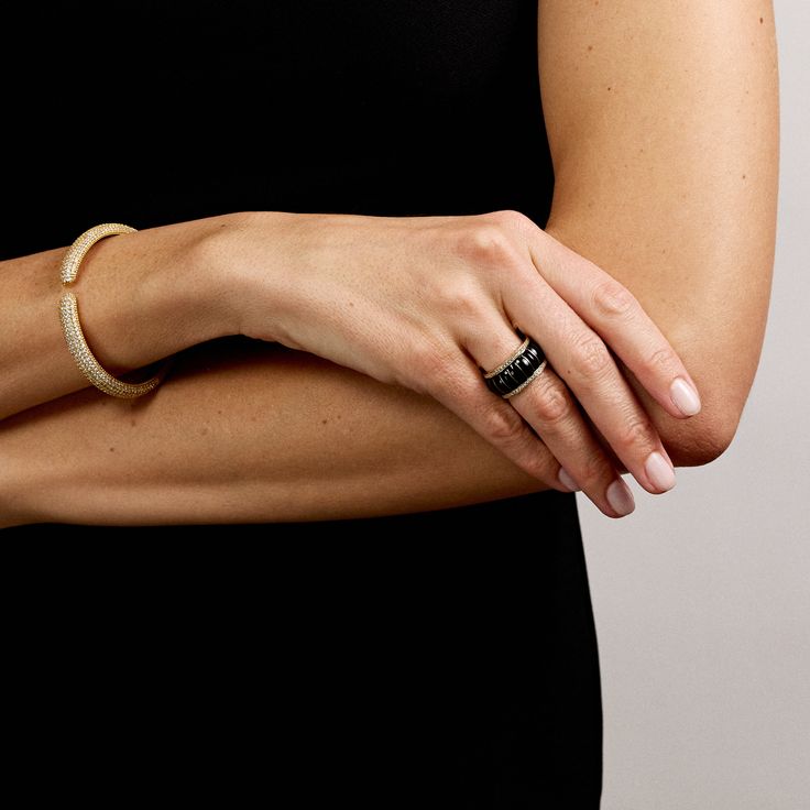 Elevate your style with the Raffles Ring in Onyx, a masterpiece of worldly jewelry that exuded both luxury and modern sophistication. This stunning enamel ring boasts a fluted design, where each ribbed section it gracefully separated by delicate gold bands, creating a refined interplay of texture and shine. The rich black enamel mimics the look of onyx, offering a glossy surface that contrasts beautifully with the warm gold accents. Adding a subtle touch of sparkle, small diamond zircons are set along the top and bottom edges, completing this ring's elegant design. Whether you're heading out for a night on the town, sipping cocktails at the Ritz, or attending a glamorous black-tie soiree, the Raffle Ring in Onyx seamlessly blends classic luxury with a contemporary twist. Part of our After Elegant Yellow Gold Enamel Ring With Polished Finish, Luxury Formal Jewelry With Fluted Bezel, Elegant Black Enamel Diamond Ring, Elegant Yellow Gold Enamel Ring, Luxury Black Enamel Ring, Elegant Black Bands For Anniversary, Elegant Black Anniversary Bands, Elegant Enamel Ring With Polished Finish For Formal Occasions, Elegant Formal Enamel Ring With Polished Finish