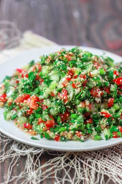 a white plate topped with cucumber and tomato salad on top of a table