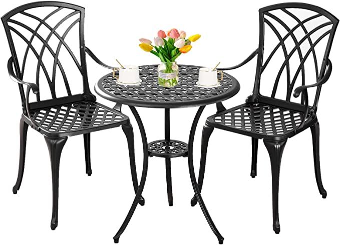 an outdoor table with two chairs and a vase filled with tulips on it