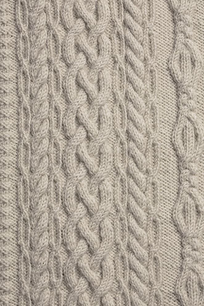 the cabled sweater is knitted and ready to be used as a coat or shawl