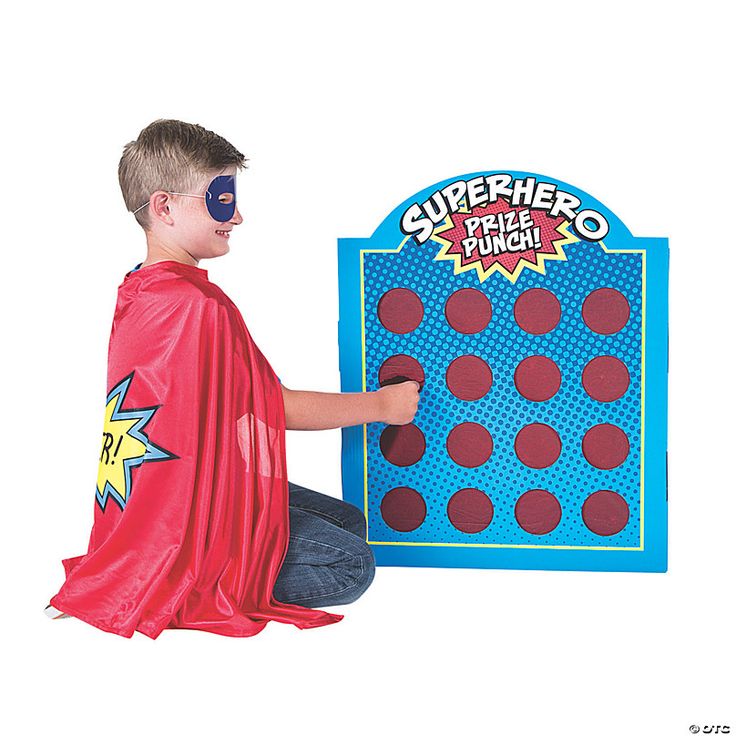 a young boy in a red cape and blue mask playing with a giant game board