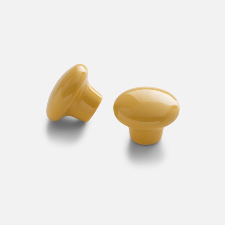 two yellow ceramic knobs on a white background, one is facing the other direction