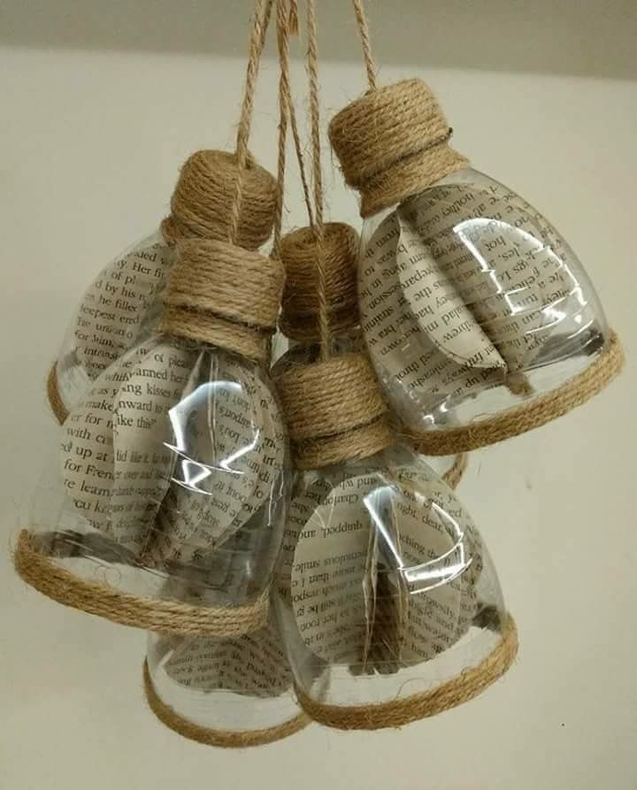 three glass bottles are hanging from twine with books printed on them and some string