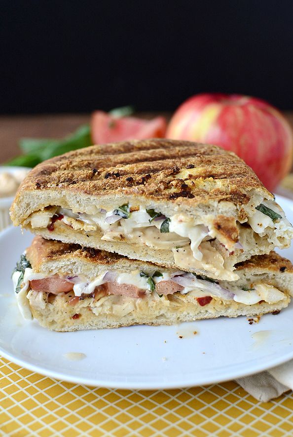 a sandwich cut in half sitting on top of a white plate next to an apple