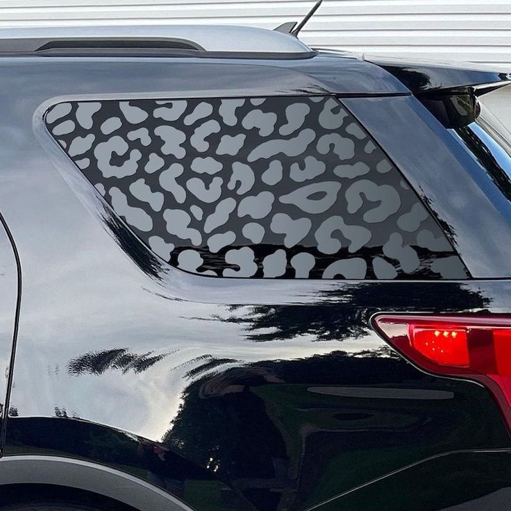 the back end of a black car with an animal print on it