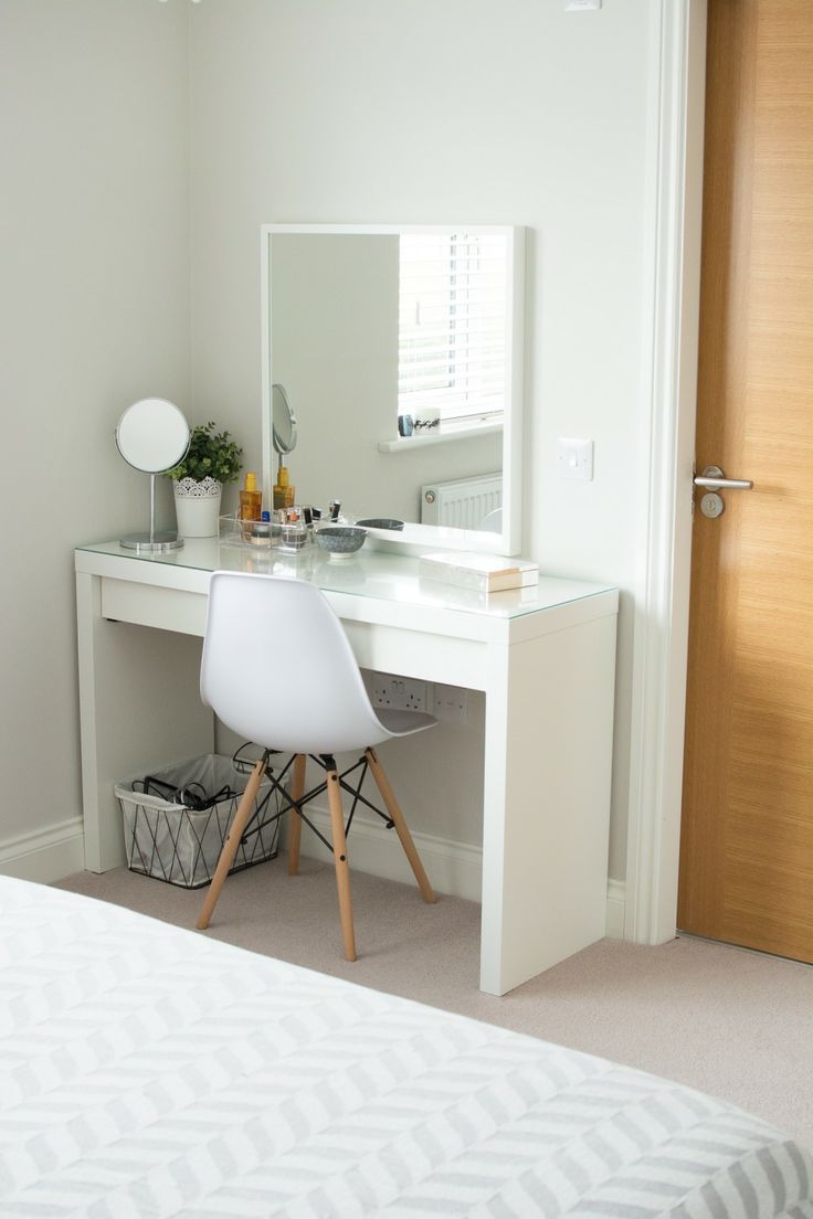 a bedroom with a white desk and mirror