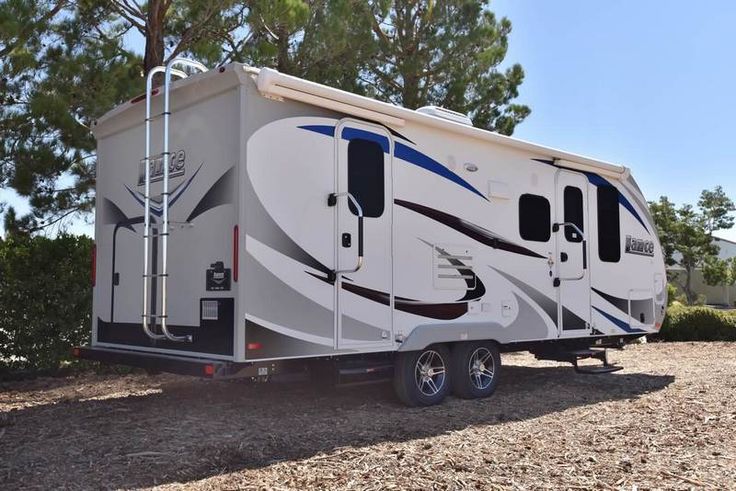 an rv parked in the dirt near some trees