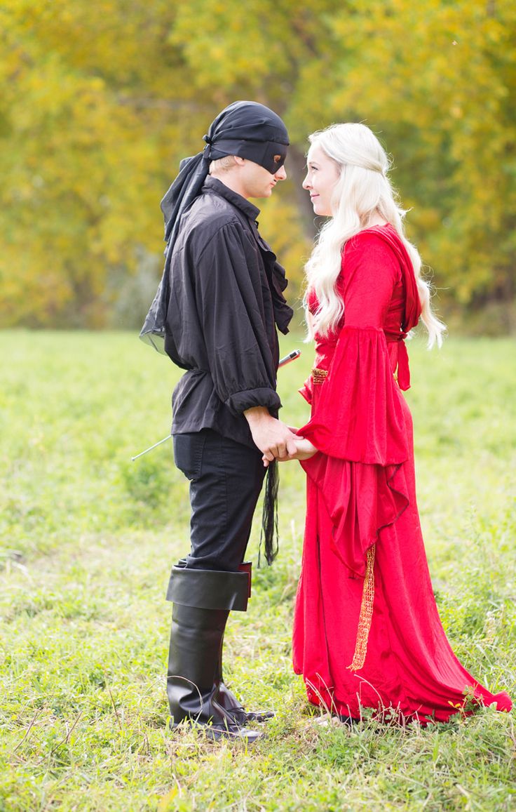 a man and woman dressed in medieval clothing standing next to each other on the grass