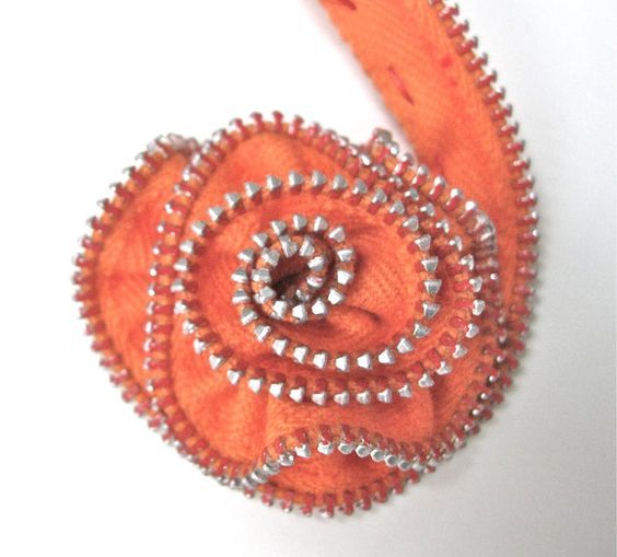 an orange brooch with silver beads on it's end and a white background