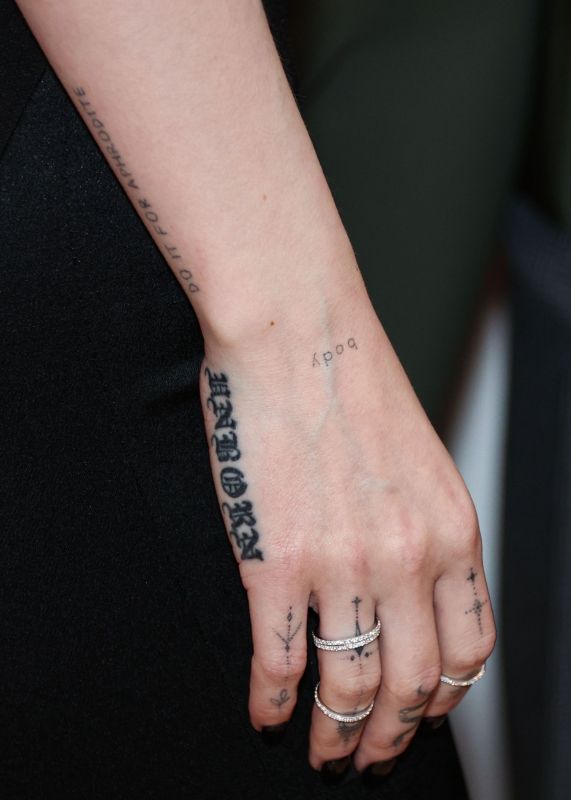 a woman's hand with tattoos on her left and right thumb in the air