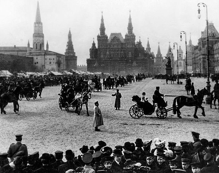 an old black and white photo of people on the street with horse drawn carriages in front of large buildings