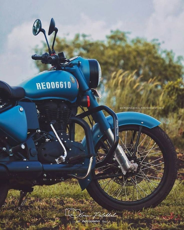 a blue motorcycle parked on top of a lush green field