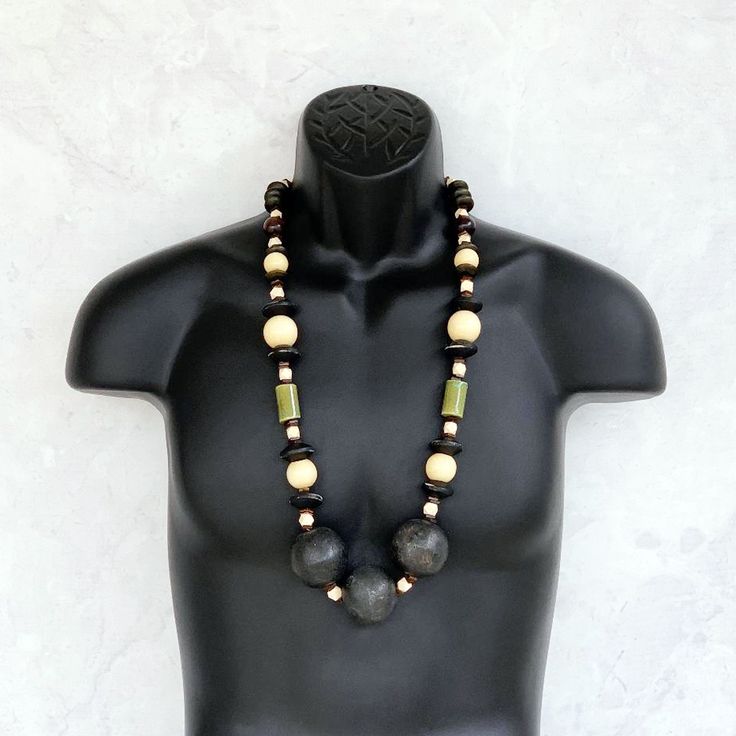 This long beaded necklace was handmade using a stylish mix of tribal beads including distressed black wooden rondelles, 25mm round beige wood beads, olive green ceramic tubes, a variety of small wooden brown beads, geometric beige wood beads, and three HUGE 40mm round distressed black wooden beads. An amazing one of a kind piece! The necklace measures 35 inches in length and is securely fastened with a sterling silver toggle clasp. Perfect for any gender! Length can be adjusted if needed - just Rustic Wooden Beads, Rustic Round Wooden Beads, Handmade Black Earthy Jewelry, Artisan Black Beaded Necklaces, Earthy Wooden Beaded Necklaces, Black Wooden Beads For Jewelry Making, Unique Black Beaded Necklaces With Large Beads, Unique Black Beaded Necklace With Large Beads, Artisan Black Necklaces With Large Beads