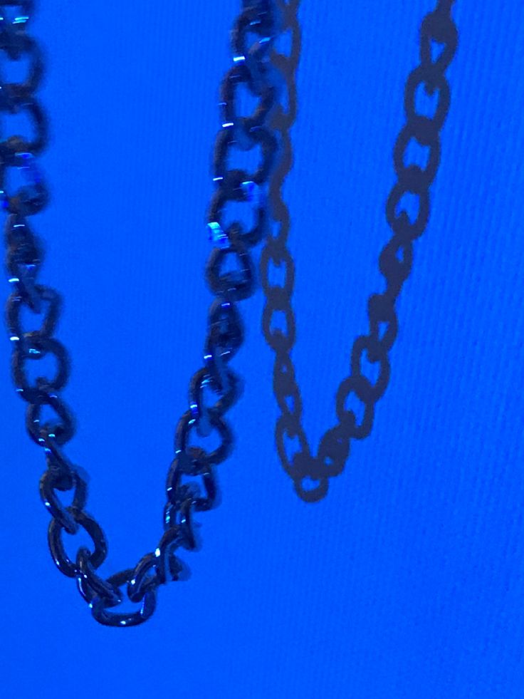 two pieces of chain hanging from the side of a blue wall with a clock on it