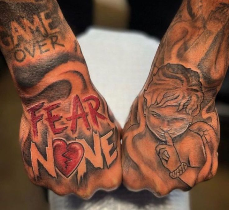 two hands with tattoos on them that say fear and one has an evil demon in the middle