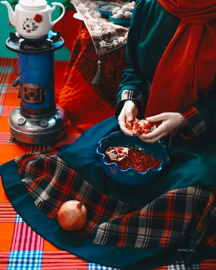 a woman sitting on a plaid table cloth holding a bowl filled with cranberry sauce