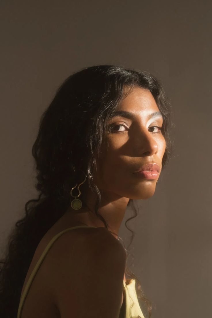 a woman with long dark hair wearing earrings