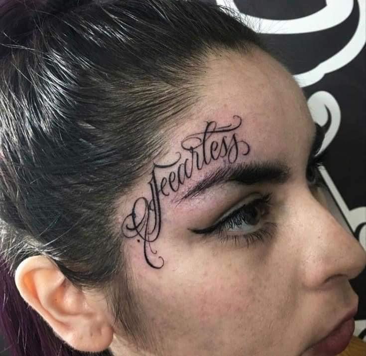 a woman with tattoos on her face and the word fearless written in cursive writing