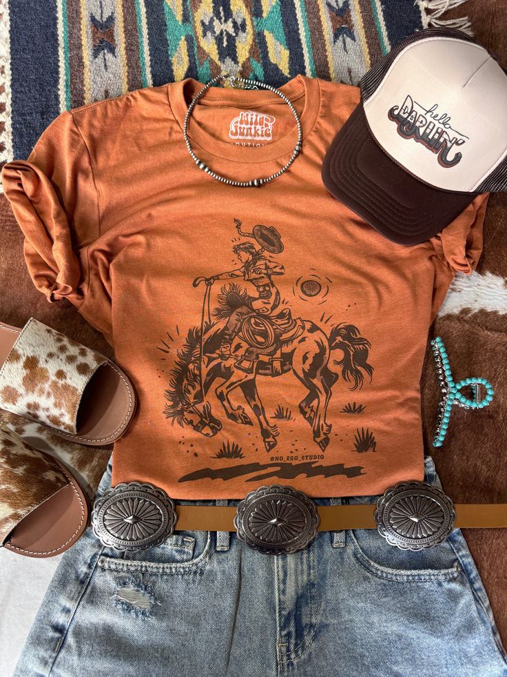 Channel your inner cowgirl with this bold and empowering tee. Featuring a striking rider graphic, it's perfect for those who embrace their wild side. Unisex fit  Made in the USA Fitted Graphic Print T-shirt For Rodeo, Western Style Relaxed Fit Graphic T-shirt, Fitted Crew Neck T-shirt For Rodeo, Western Style Relaxed Fit T-shirt With Graphic Print, Fitted Graphic Print T-shirt For Ranch, Western Style Brown Tops For Ranch, Crew Neck Top With Graphic Print For Western-themed Events, Graphic Print Crew Neck Tops For Western-themed Events, Western-themed Graphic Print Cotton Tops