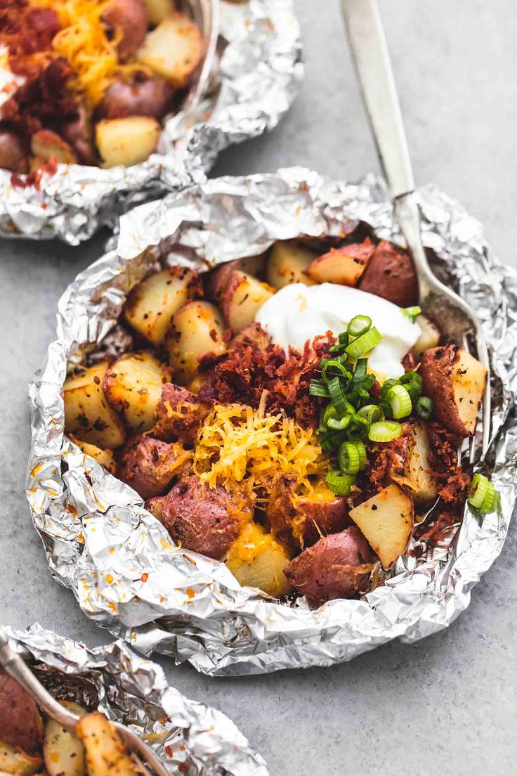 three foil packets filled with potatoes and meat