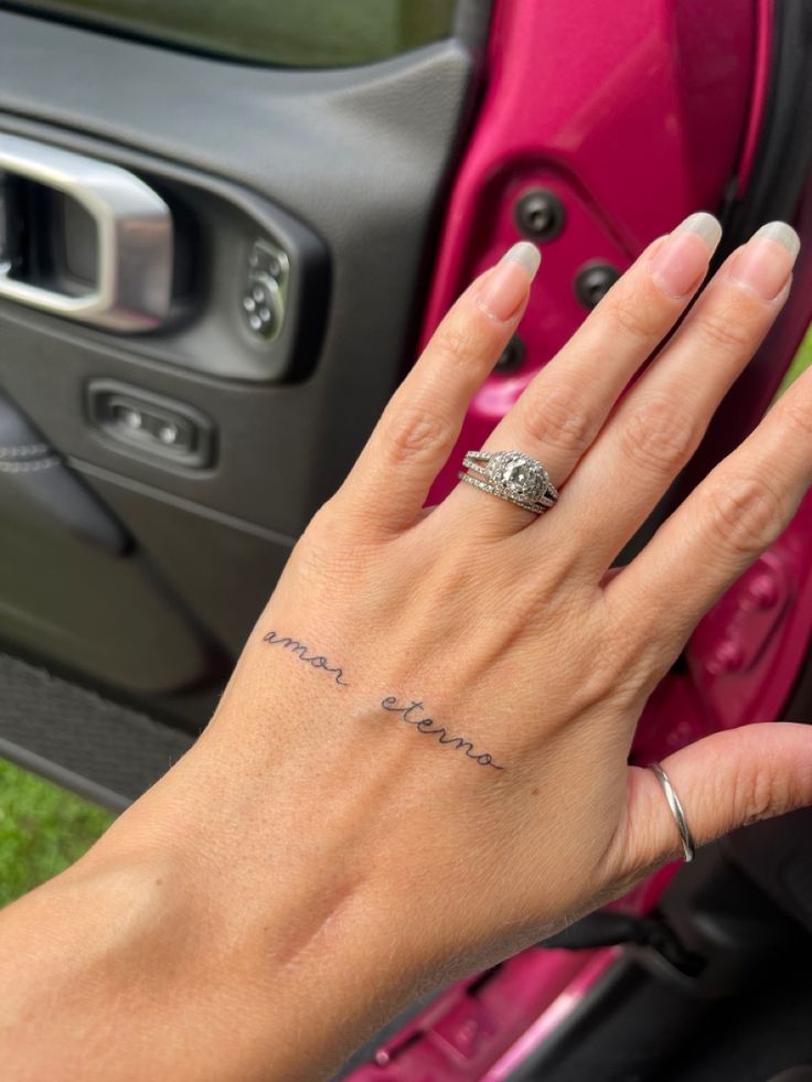 a woman's hand with a ring on her finger next to a car door