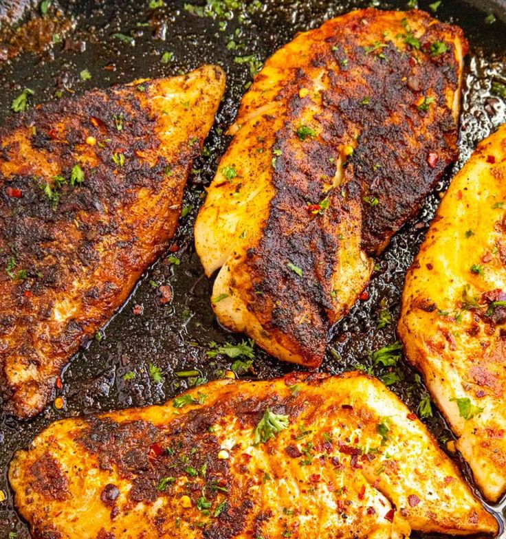 three pieces of chicken cooking in a skillet