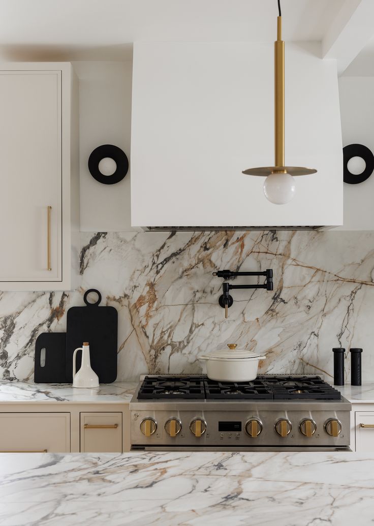 a kitchen with marble counter tops and gold accents on the hood, stove top and oven